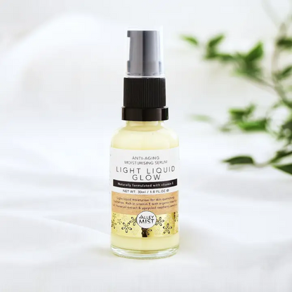 Bottle of Valley Mist Light Liquid Glow serum with pump on a white background with greenery.