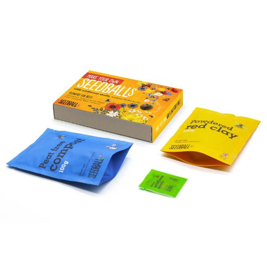 Seedball kit with packaging, coloured powders, and labels on a white background