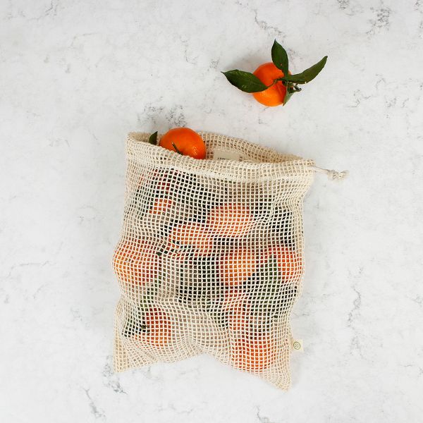 Mesh produce bag filled with oranges on a light gray surface