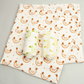 Organic cotton set of three muslin cloths, one shown opened out and the other two rolled up. All with cream background then colourful fruity images 