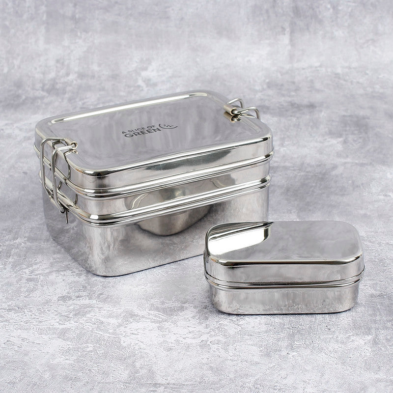 Stainless steel two tier lunch box shown sealed tight with separate tin (lid on) on a grey background.
