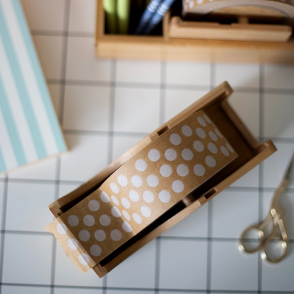 Wooden paper tape dispenser bag with brown tape and white polka dots on a craft table.