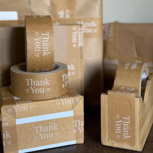 Brown paper tape with 'Thank You' text on bamboo paper tape dispenser and boxes.