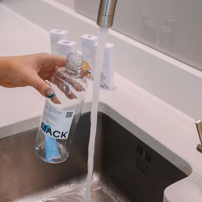 Mack reusable bottle with pod inside being filled with water at a sink