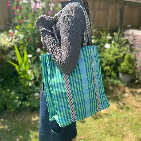 Recycled cement sack in 'Ocean' colourway (blue and green stripes) shown in use on somebody's shoulder