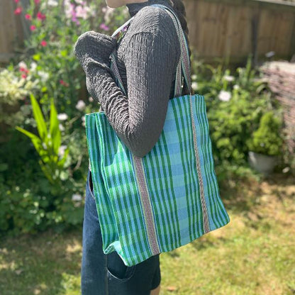 Recycled cement sack in 'Ocean' colourway (blue and green stripes) shown in use on somebody's shoulder
