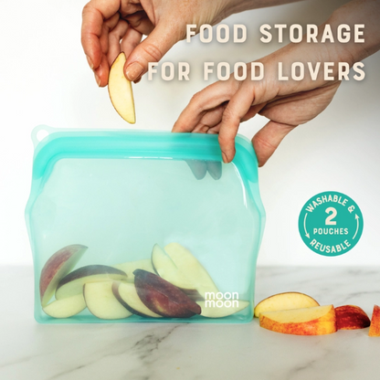 Reusable silicone food bags in medium shown with fruit slices being put inside