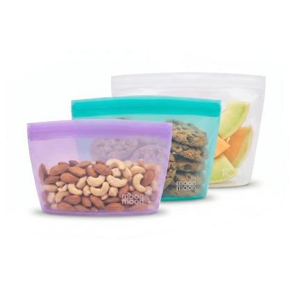 Set of reusable silicone food storage bags with snacks on a white background