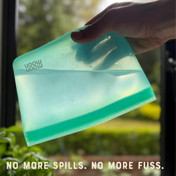Green silicone food bag held by a hand upside down with water inside and text reading "No more spills. No more fuss."