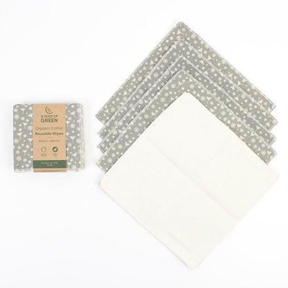 A set of reusable cotton wipes by A Slice of Green, including one packaged wipe with a brown paper label and five unfolded wipes showing a grey and white floral pattern on one side and a solid cream-colored reverse side.