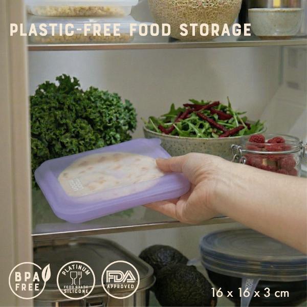 Person putting a silicone sandwich case in a refrigerator with various foods and text reading "plastic-free food storage"
