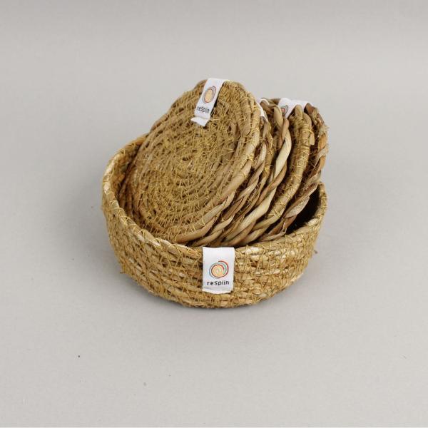 Set of 6 natural seagrass coasters with a holder, laid on a pale background