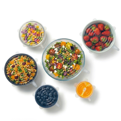 Set of salad bowls and fruit with various ingredients and different size silicone lids on a white background