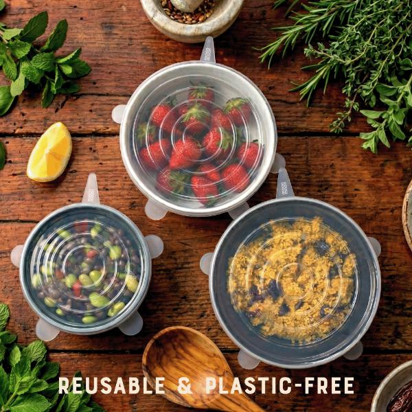 Reusable silicone food covers over bowls containing different foodstuffs on a wooden surface with fresh ingredients