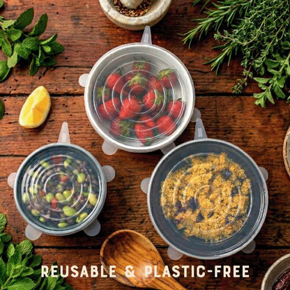 Reusable silicone food covers over bowls containing different foodstuffs on a wooden surface with fresh ingredients