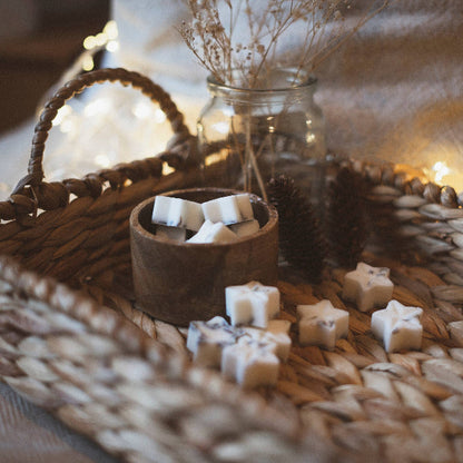 Star-shaped wax melts shown in wooden pot on a wooden woven tray