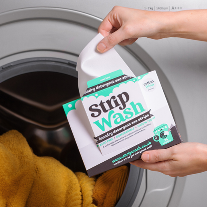 Eco laundry detergent strips in cardboard packaging with a hand taking one out of the box to pop in the washing machine