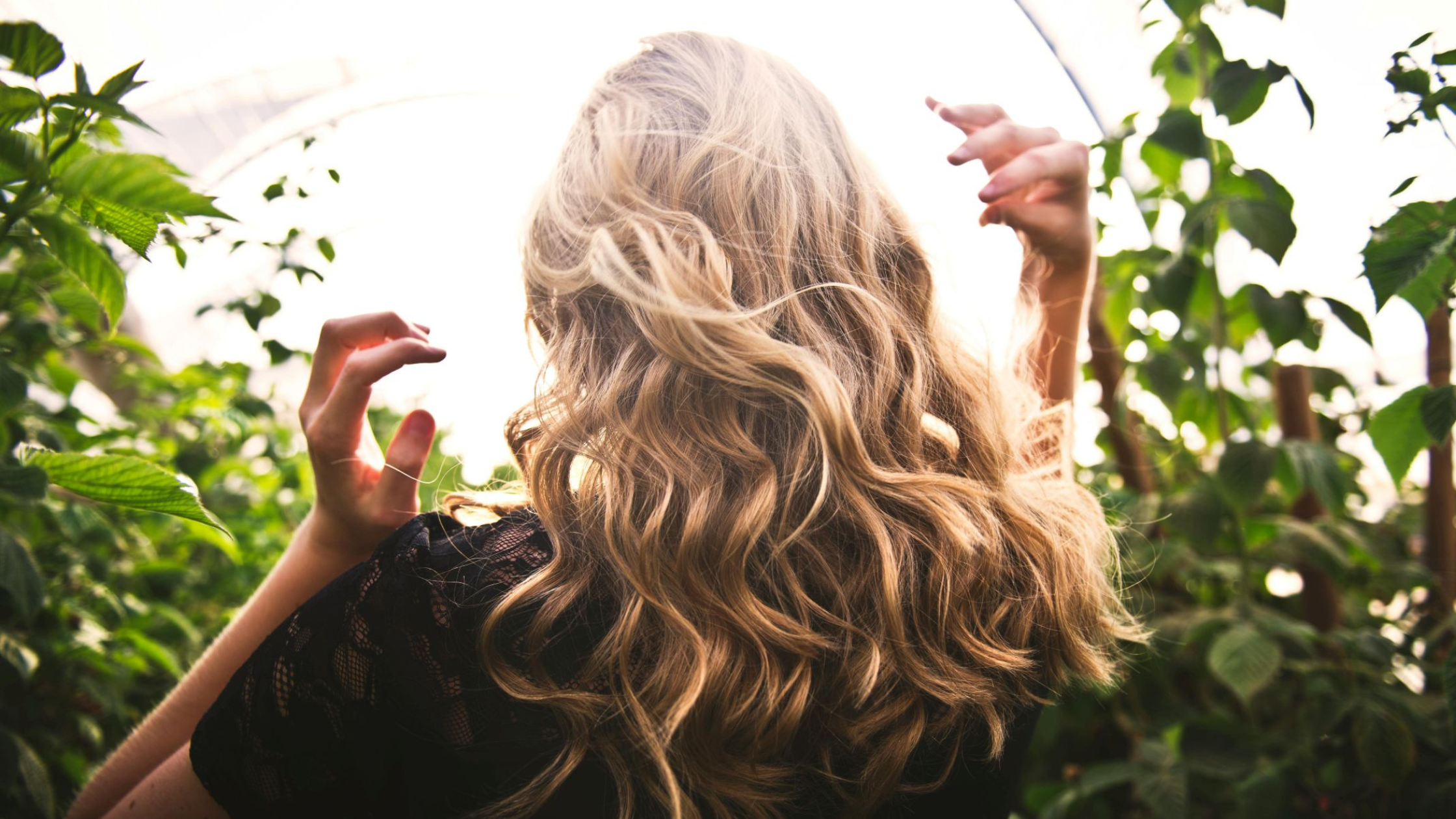 Person with blonde hair standing among green plants Photo by Tim Mossholder