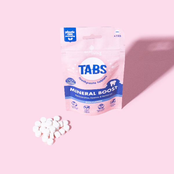 Package of Tabs Mineral Boost toothpaste tablets on a pink background in paper packaging with tabs alongside