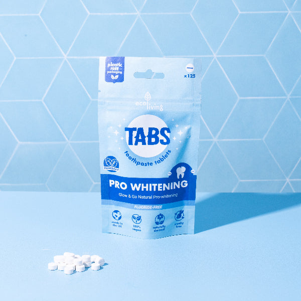 Package of Tabs Pro Whitening toothpaste tablets on a blue geometric background in paper packaging with tabs alongside