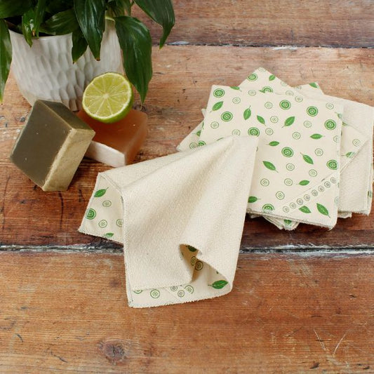 Set of reusable cloth paper towels with green mint pattern on a wooden surface with soap and lime.