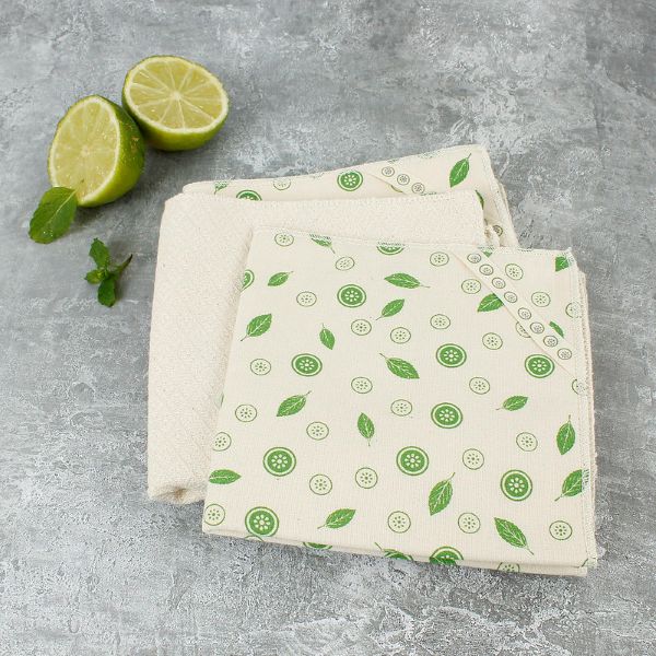Set of organic cotton paper towels with green mint pattern on a marble background shown unwrapped next to sliced lime