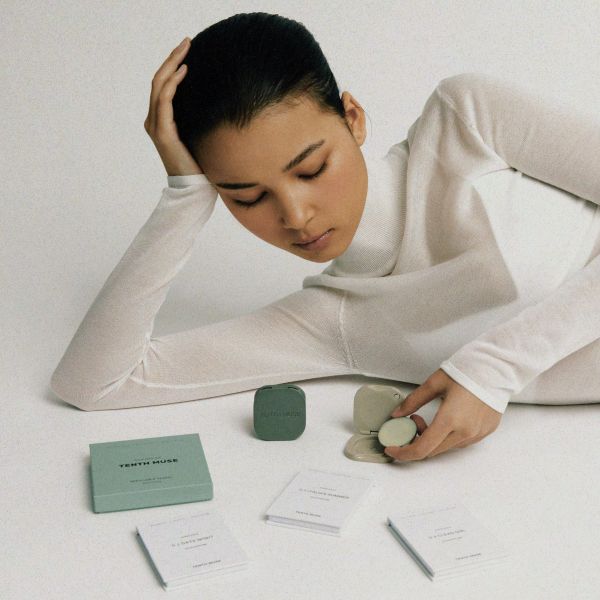 Clay and matcha vessels shown with perfume balms alongside and model inserting a balm into the vessel