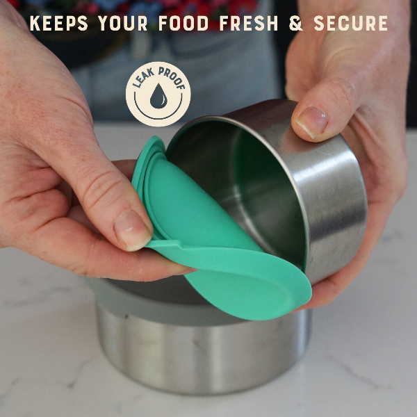 Moonmoon metal pot with a green lid being held by hands, with text reading 'Keeps your food fresh & secure' and 'Leak Proof' logo.