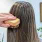 Person using wooden detangling hairbrush on their hair with a blurred background
