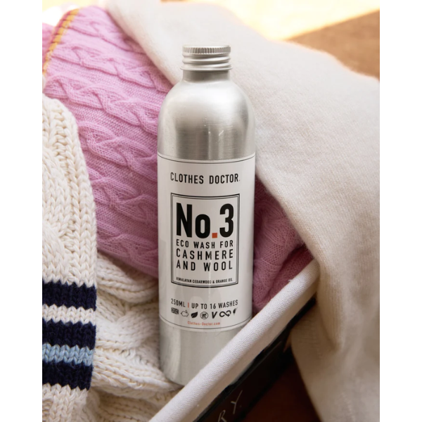 Laundry detergent for cashmere and wool shown next to cashmere sweaters