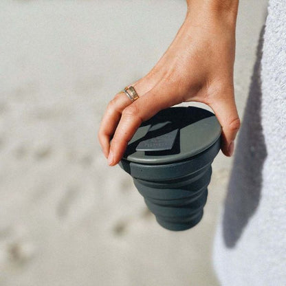 Hunu collapsible reusable cup with charcoal design held in hand, portable and eco-friendly for on-the-go drinking.