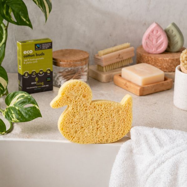 Bathroom shelf with eco-friendly products including a duck-shaped sponge, cotton buds, and soap bar on a wooden soapdish