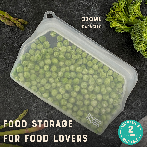 Silicone food storage bag with peas on a dark surface, featuring 'moon moon' branding.