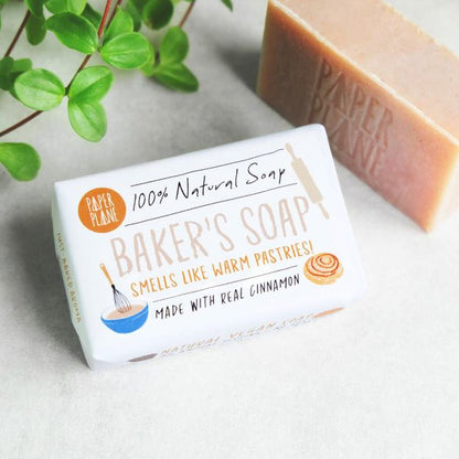 Paper Plane baker's soap showing wrapped and unwrapped, packaging reads "100% natural soap, Smells like warm pastries, Made with real cinnamon"