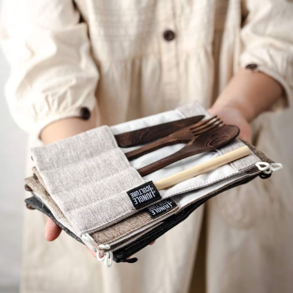 Person holding sets of wooden cutlery with top one open showing dark wood cutlery and straw inside