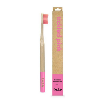 Bamboo toothbrush tickled pink (pink bristles and tip of brush) shown alongside cardboard box