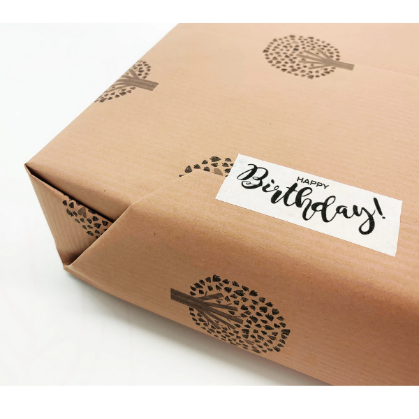 Eco-friendly paper tape (white) with  "Happy Birthday!" written  in black font attached to a brown paper parcel