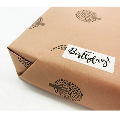 Eco-friendly paper tape (white) with  "Happy Birthday!" written  in black font attached to a brown paper parcel