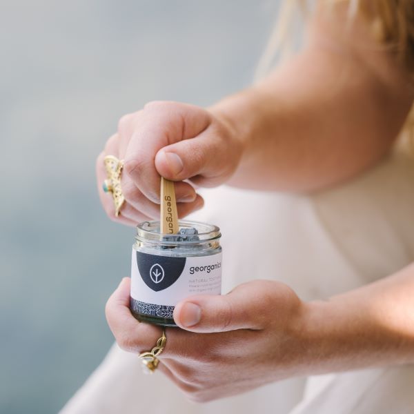 Toothpaste in activated charcoal being scooped out of jar